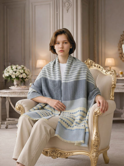 Noori Couture grey, white, and pale yellow striped herringbone cashmere scarf draped on a model sitting in an ornate chair.