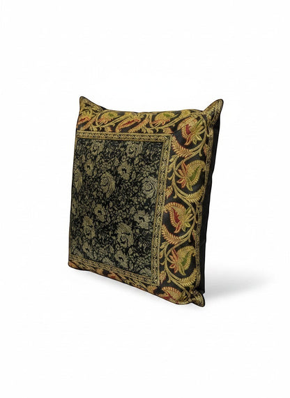 Noori Couture black brocade cushion cover with intricate gold, red, and green floral and paisley motifs. Rich texture.