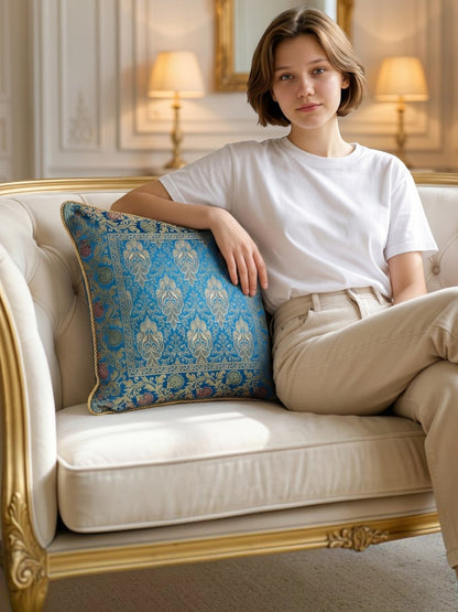 Noori Couture blue cushion cover with gold intricate woven patterns and floral border. Textured fabric, decorative accent.