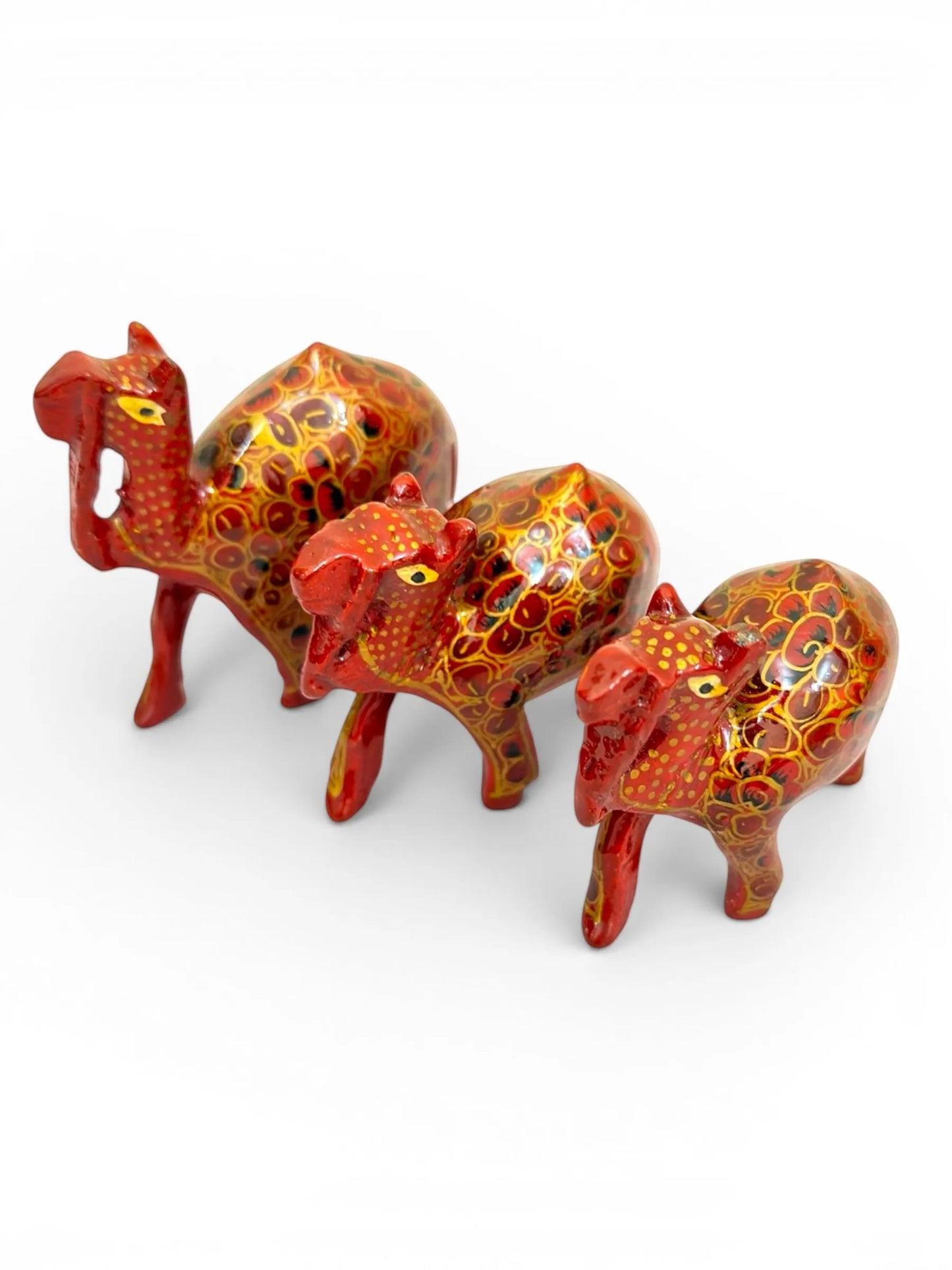 Noori Couture set of 3 red papier-mâché camel figurines with intricate gold floral detailing and yellow eyes.