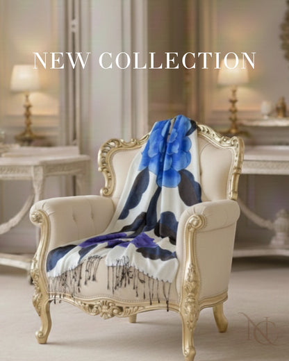 Noori Couture limited edition hand-painted shawl in white with large blue floral print, draped over an ornate cream armchair