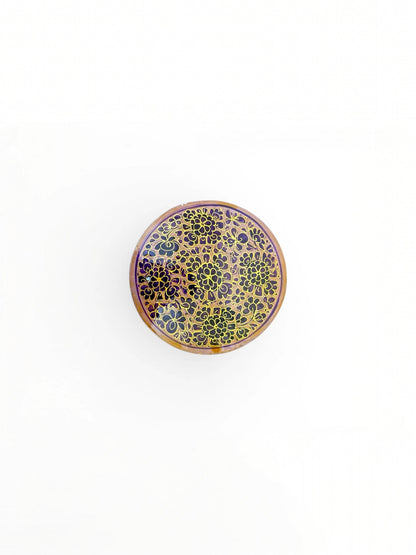 Noori Couture handpainted papier-mâché round coaster with intricate gold floral pattern on a purple background.