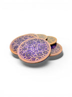 Noori Couture handpainted papier-mâché coasters with intricate floral patterns in purple and gold on a natural wood base.
