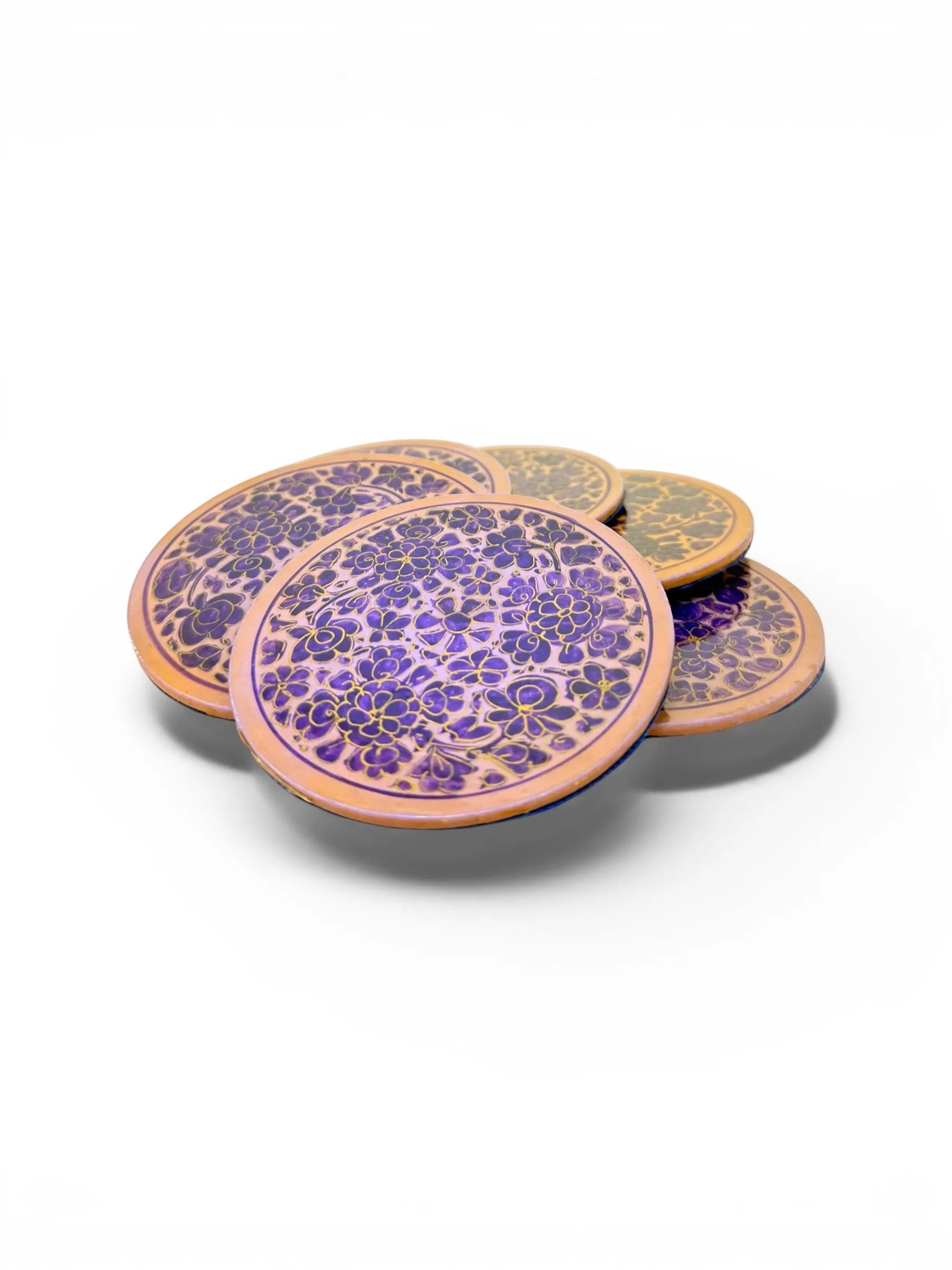 Noori Couture handpainted papier-mâché coasters with intricate floral patterns in purple and gold on a natural wood base.