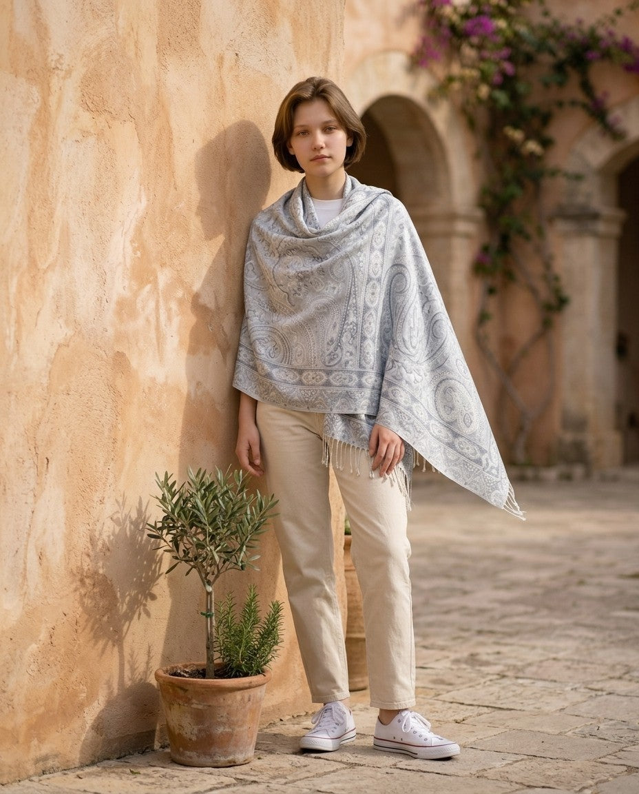 Noori Couture handwoven mulberry silk shawl with grey paisley pattern draped over a woman in a Mediterranean courtyard