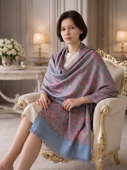 Noori Couture pashmina shawl in blue with a multi-colored paisley pattern, draped over a woman in a classic interior.