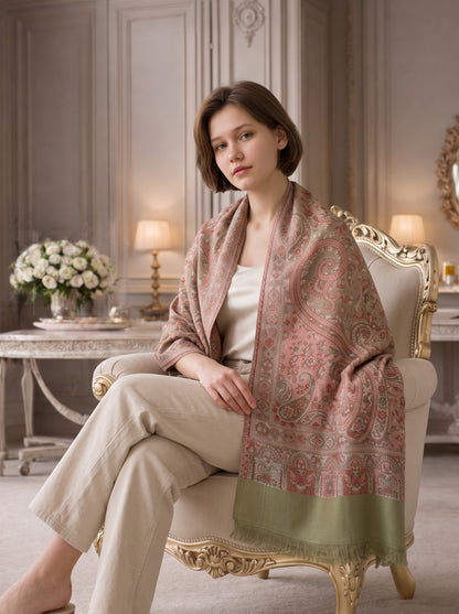 Noori Couture paisley pashmina shawl in sage green and rose draped over a woman sitting in a classic armchair