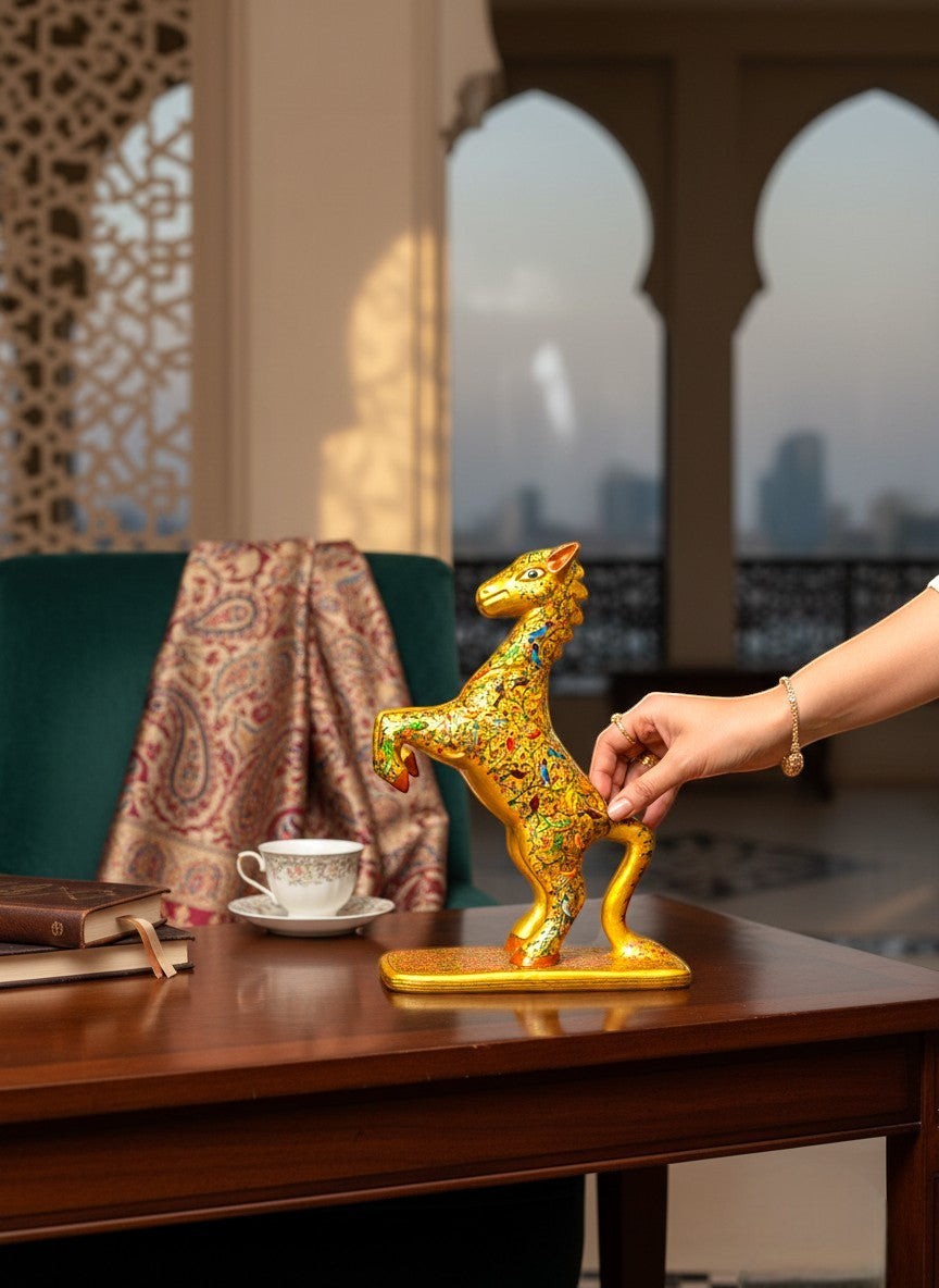 Noori Couture hand-painted paper mâché horse sculpture, gold with intricate floral and bird motifs on a decorative base.