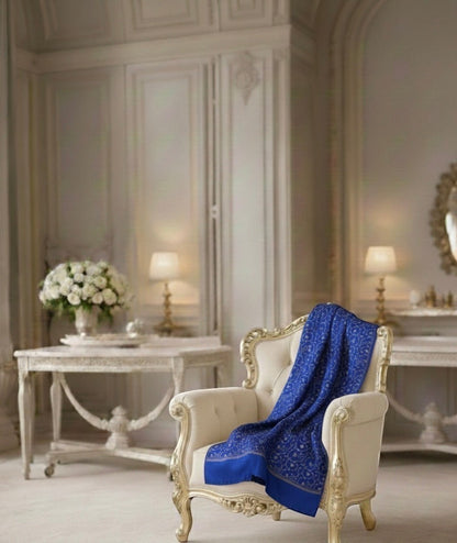 Noori Couture royal blue handwoven shawl with intricate Sozni Jali embroidery draped on an ornate cream armchair.