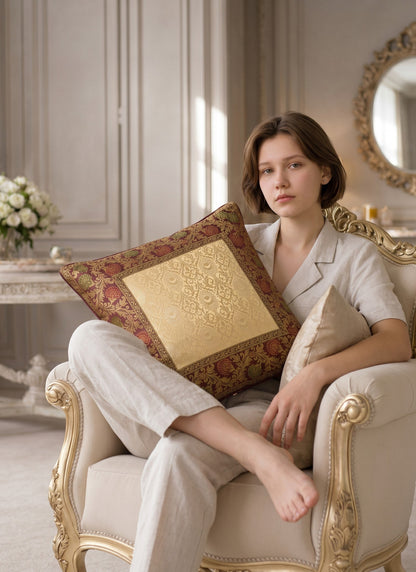 Noori Couture Royal Cushion Cover in gold brocade with intricate zari detailing and floral motifs in burgundy and green.