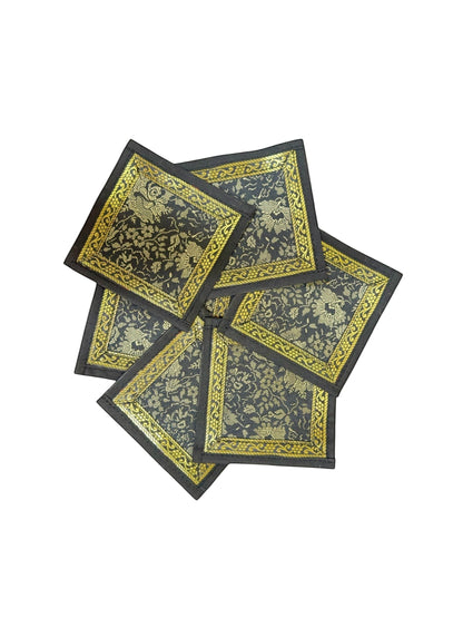 Noori Couture Royal Dining Set coasters with gold floral pattern on black fabric and gold border.