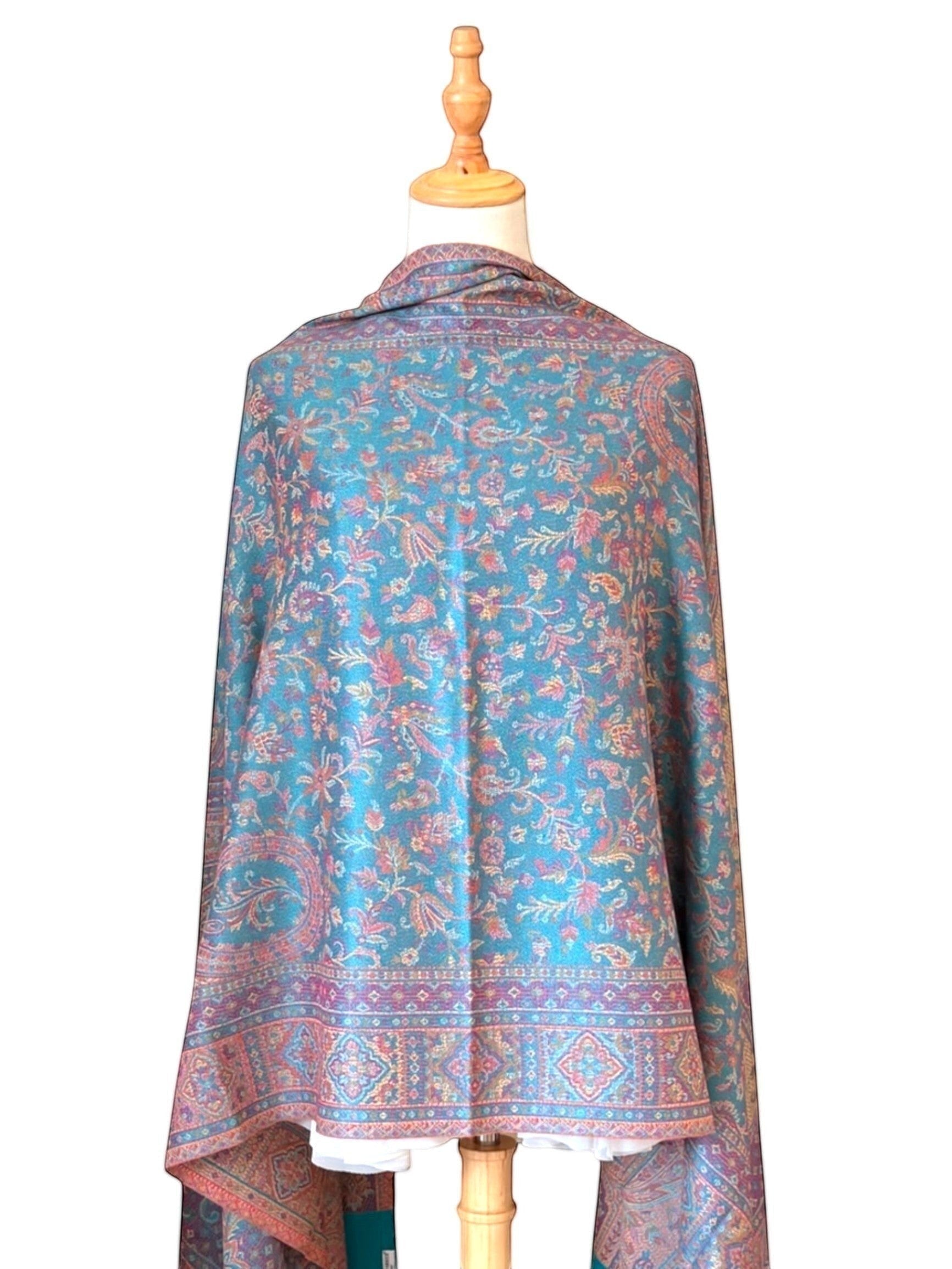 Noori Couture pashmina shawl in teal with intricate violet and gold paisley and geometric patterns and fringed hem.
